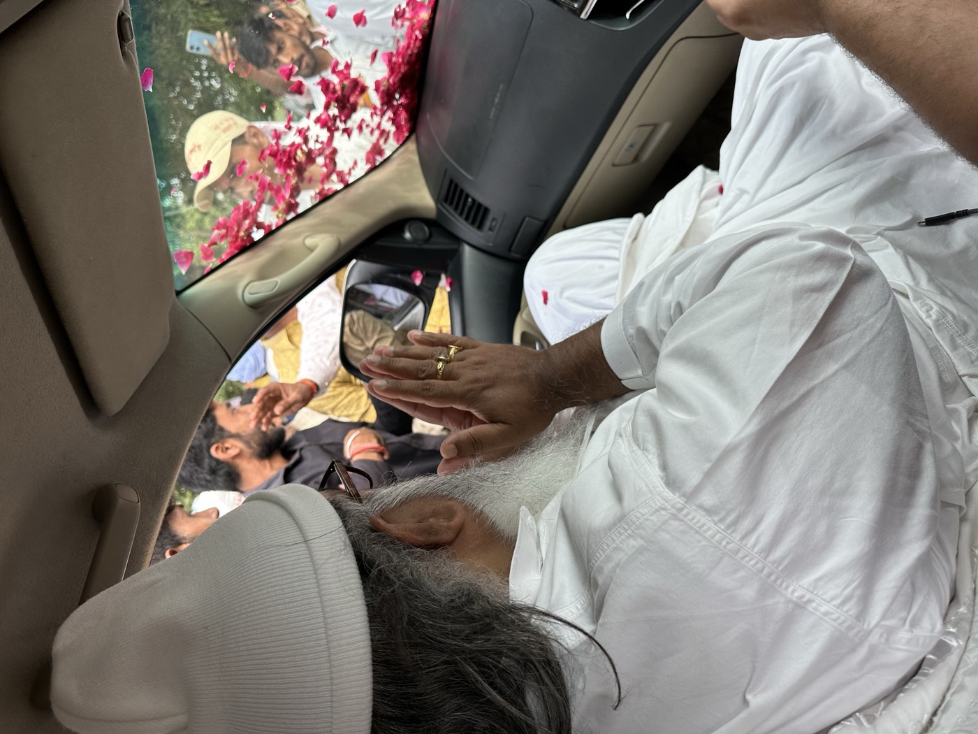 Devotees greet Guruji with folded hands and flowers